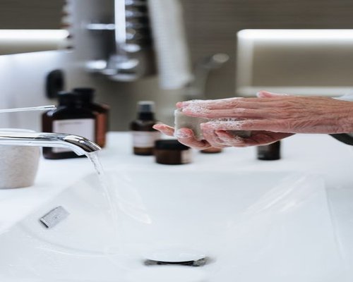 Person meticulously washing hands with soap under running tap water